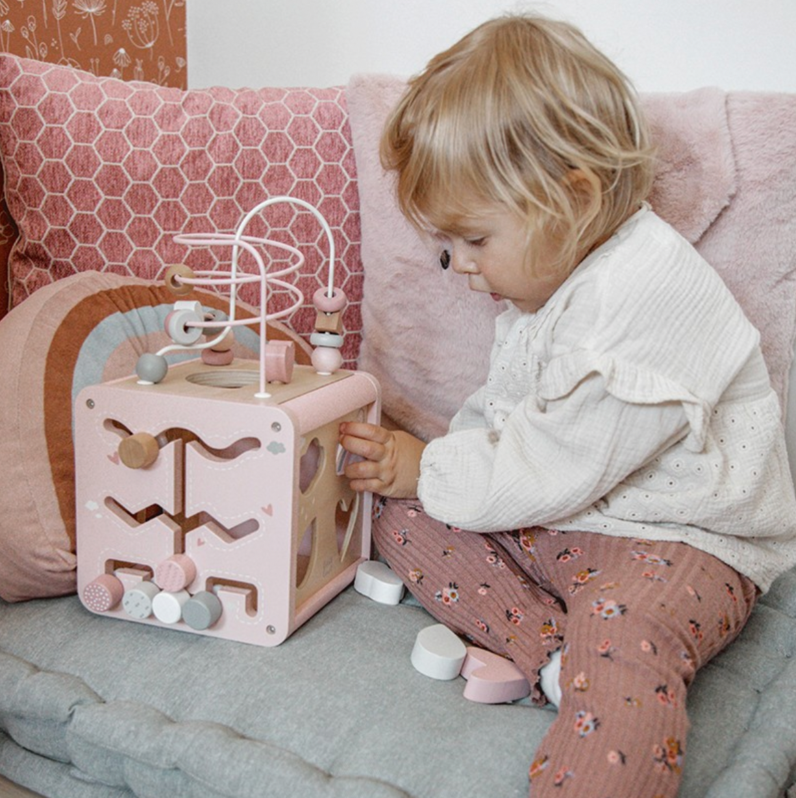 Mädchen spielt mit Motorikwürfel in rosa 