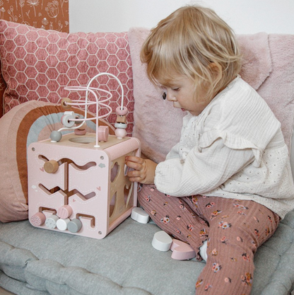 Mädchen spielt mit Motorikwürfel in rosa 
