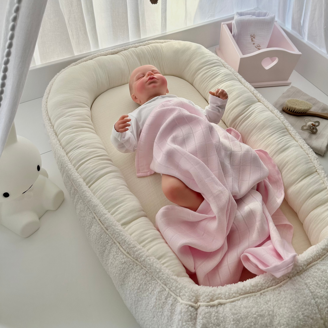 Baby liegt im Babynest aus Bio-Baumwolle und Boucle, auf der Wickelkommode