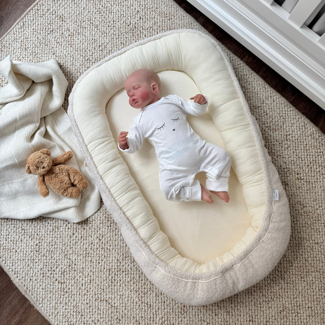 Babyliegt im Babynest aus Bio-Baumwolle und weichem Boucle 