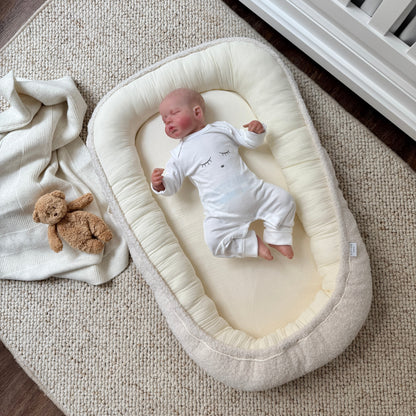 Babyliegt im Babynest aus Bio-Baumwolle und weichem Boucle 