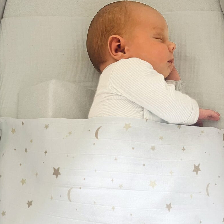 Baby zugedeckt mit einem Pucktuch Swaddle weiß mit Mond &amp; Sternen von Poetree Kids 